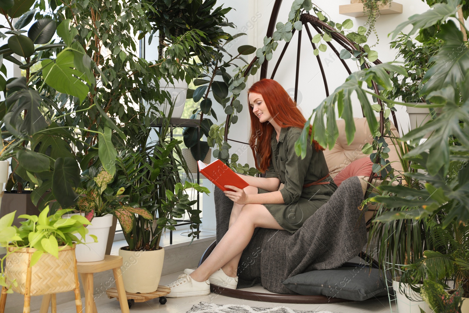 Photo of Happy beautiful woman reading book in egg chair at home