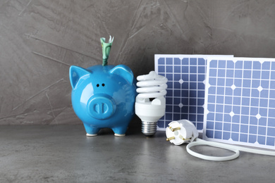 Photo of Composition with solar panels and piggy bank on grey stone table
