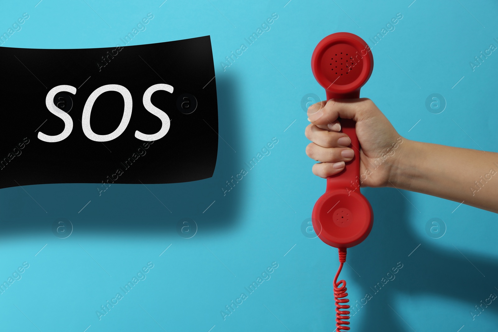 Image of Woman holding telephone handset on light blue background, closeup. Emergency SOS call