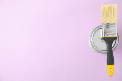 Photo of Closed can of paint with brush on color background, top view. Space for text
