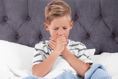 Photo of Ill boy suffering from cough in bed at home