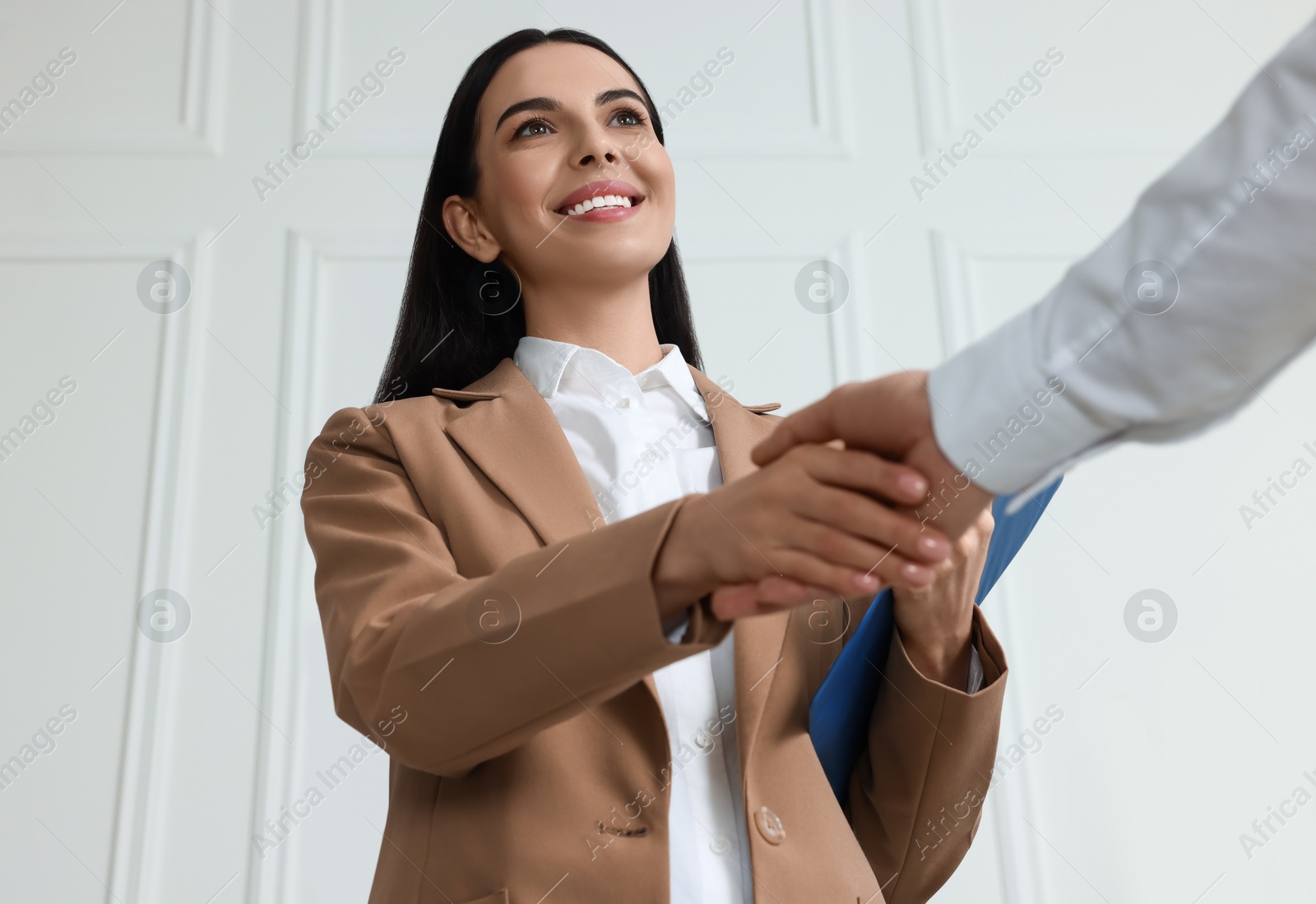 Photo of Human resources manager shaking hands with applicant during job interview in office