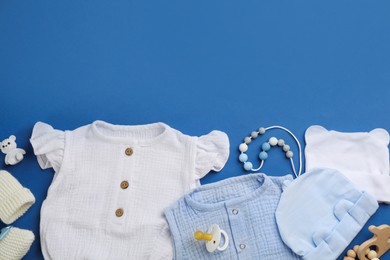 Flat lay composition with baby clothes and accessories on blue background, space for text