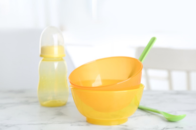 Photo of Set of plastic dishware on white marble table indoors. Serving baby food