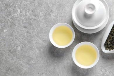 Photo of Flat lay composition with cups of Tie Guan Yin oolong tea and space for text on grey background