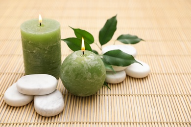 Photo of Composition with spa stones and candles on bamboo mat