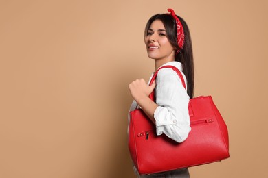 Photo of Young woman with stylish bag on beige background, space for text