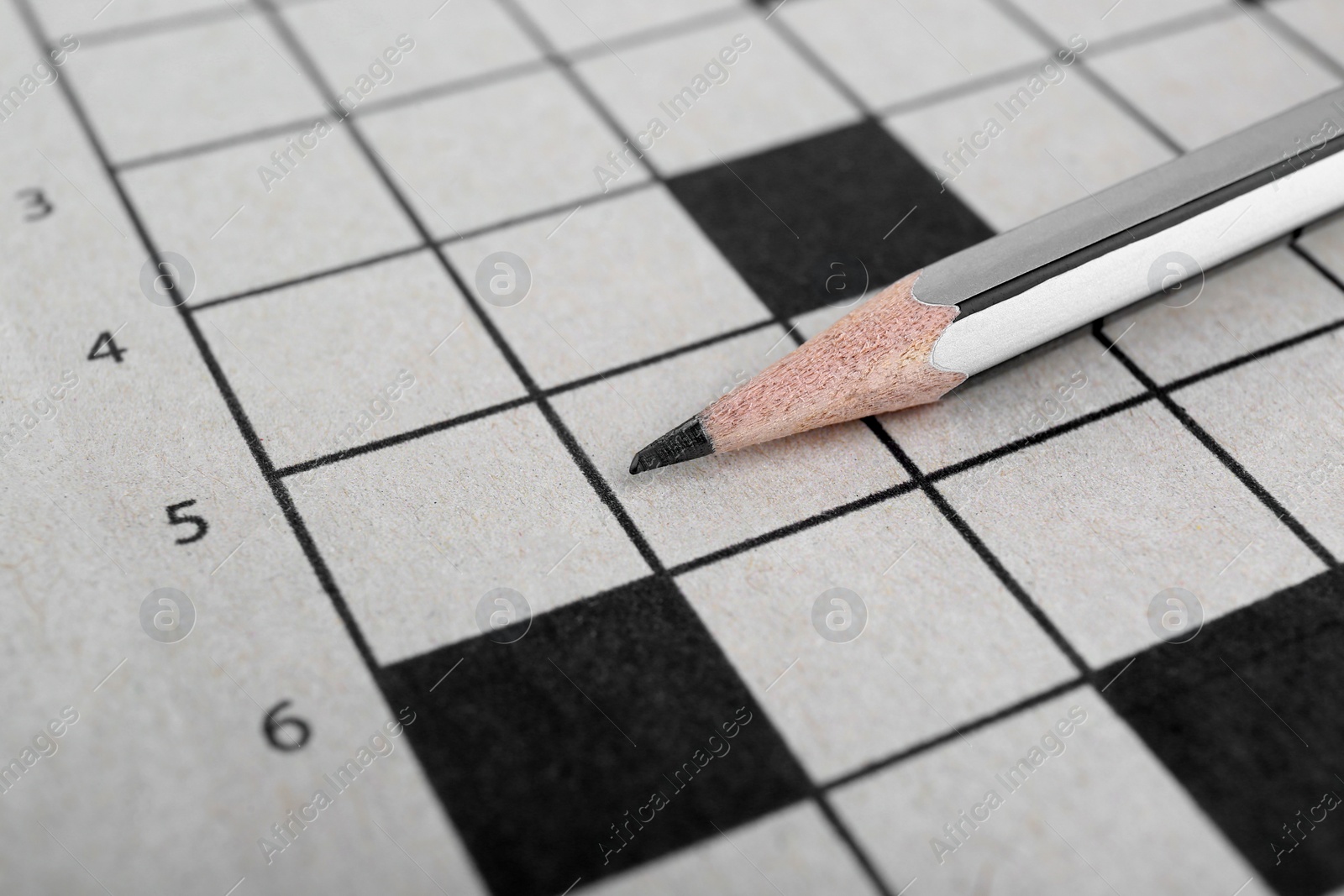 Photo of Pencil on blank crossword, closeup view. Space for text