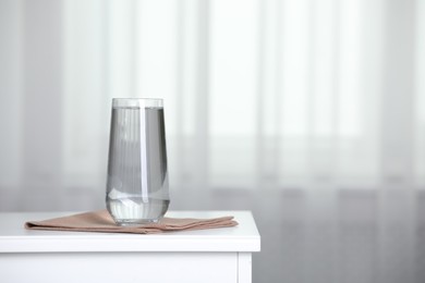 Photo of Glass of pure water on white wooden table indoors, space for text