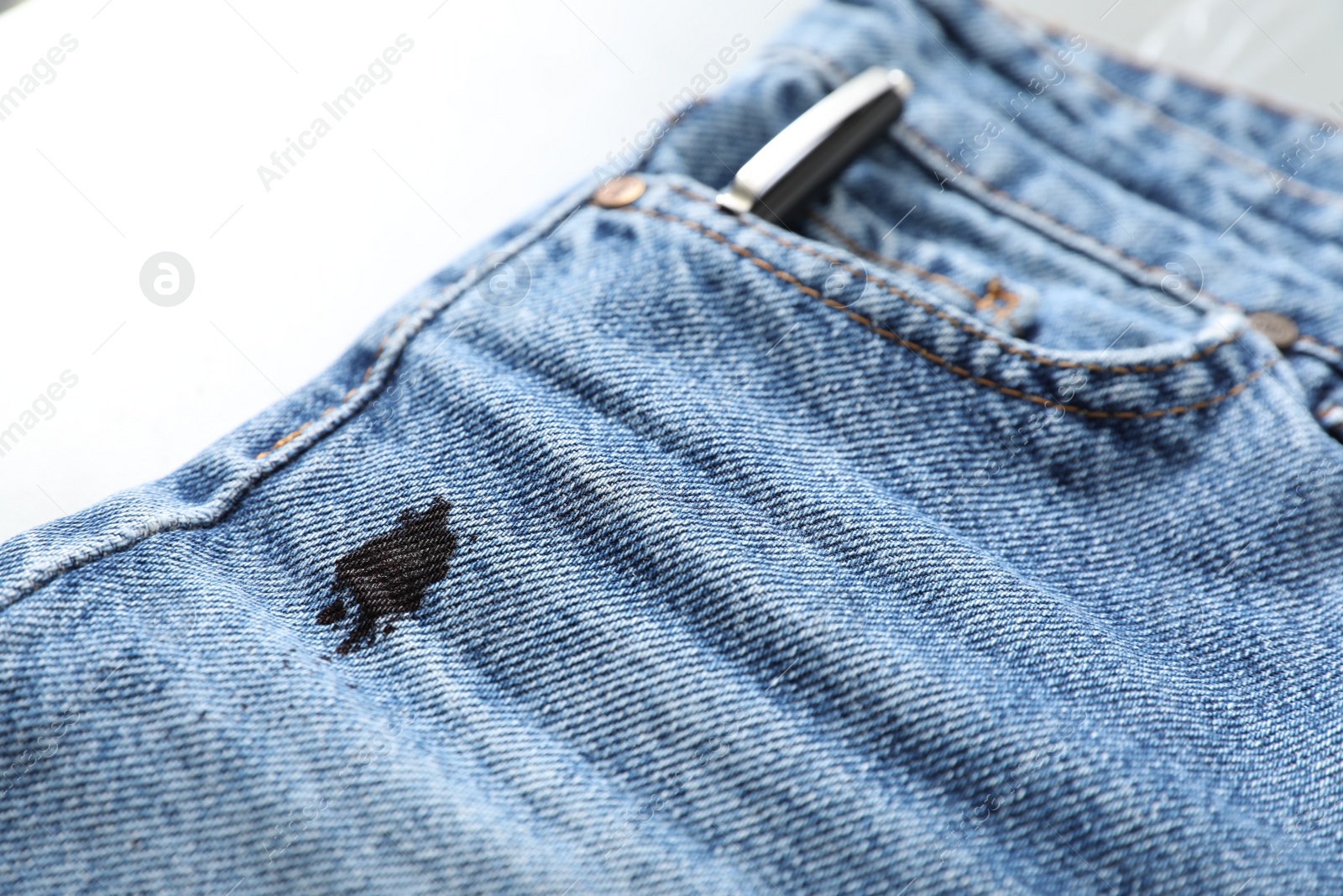 Photo of Jeans with black ink stain on light background, closeup