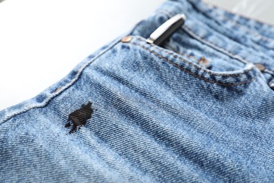 Jeans with black ink stain on light background, closeup