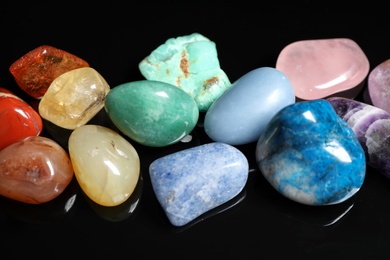 Photo of Pile of different beautiful gemstones on black background