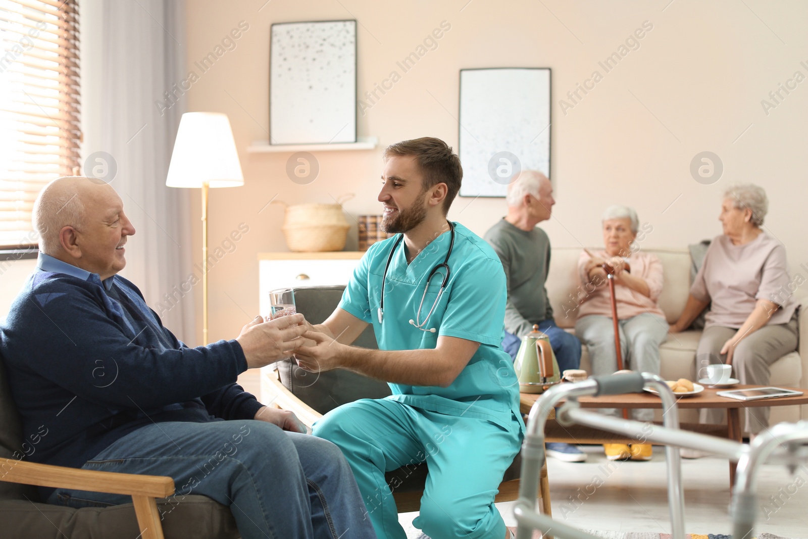 Photo of Care worker giving water to elderly woman in geriatric hospice