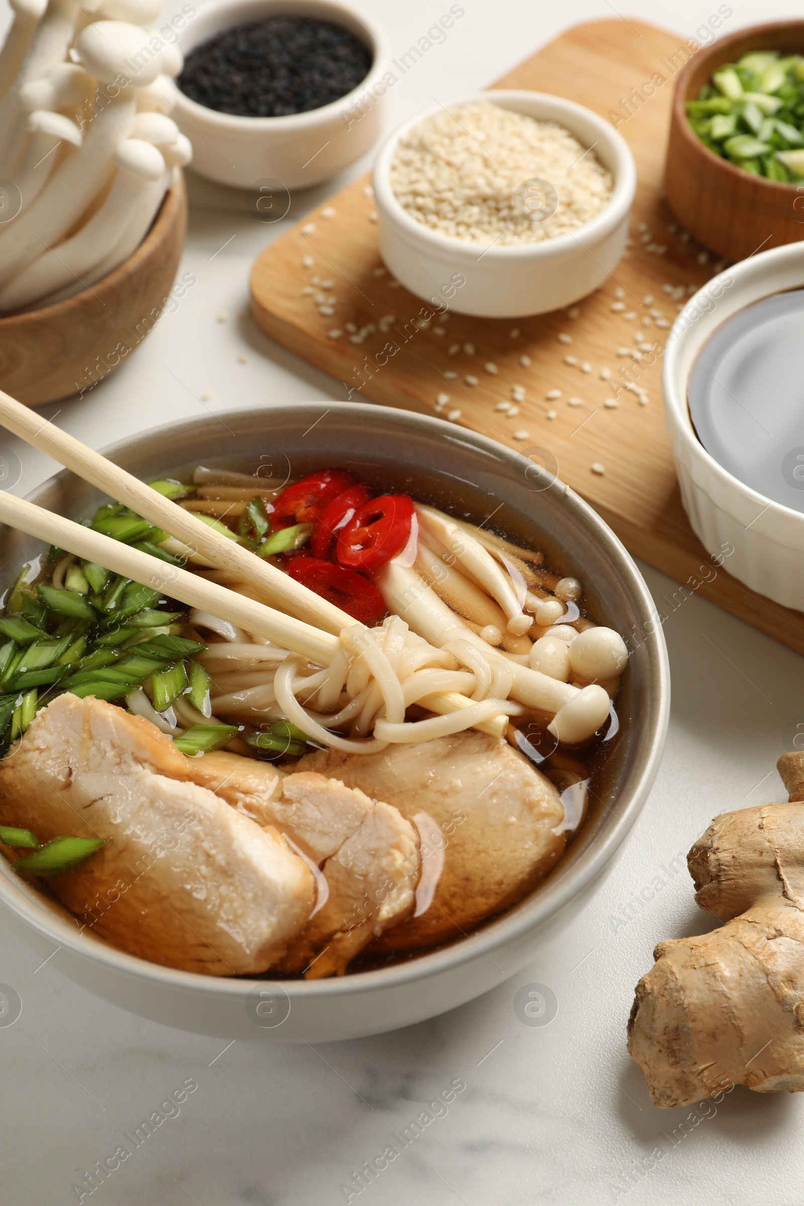 Photo of Delicious ramen with meat and ingredients on white marble table. Noodle soup