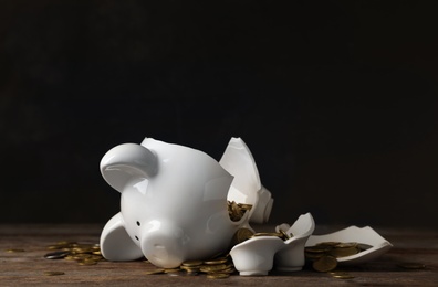 Photo of Broken piggy bank with money on table against dark background