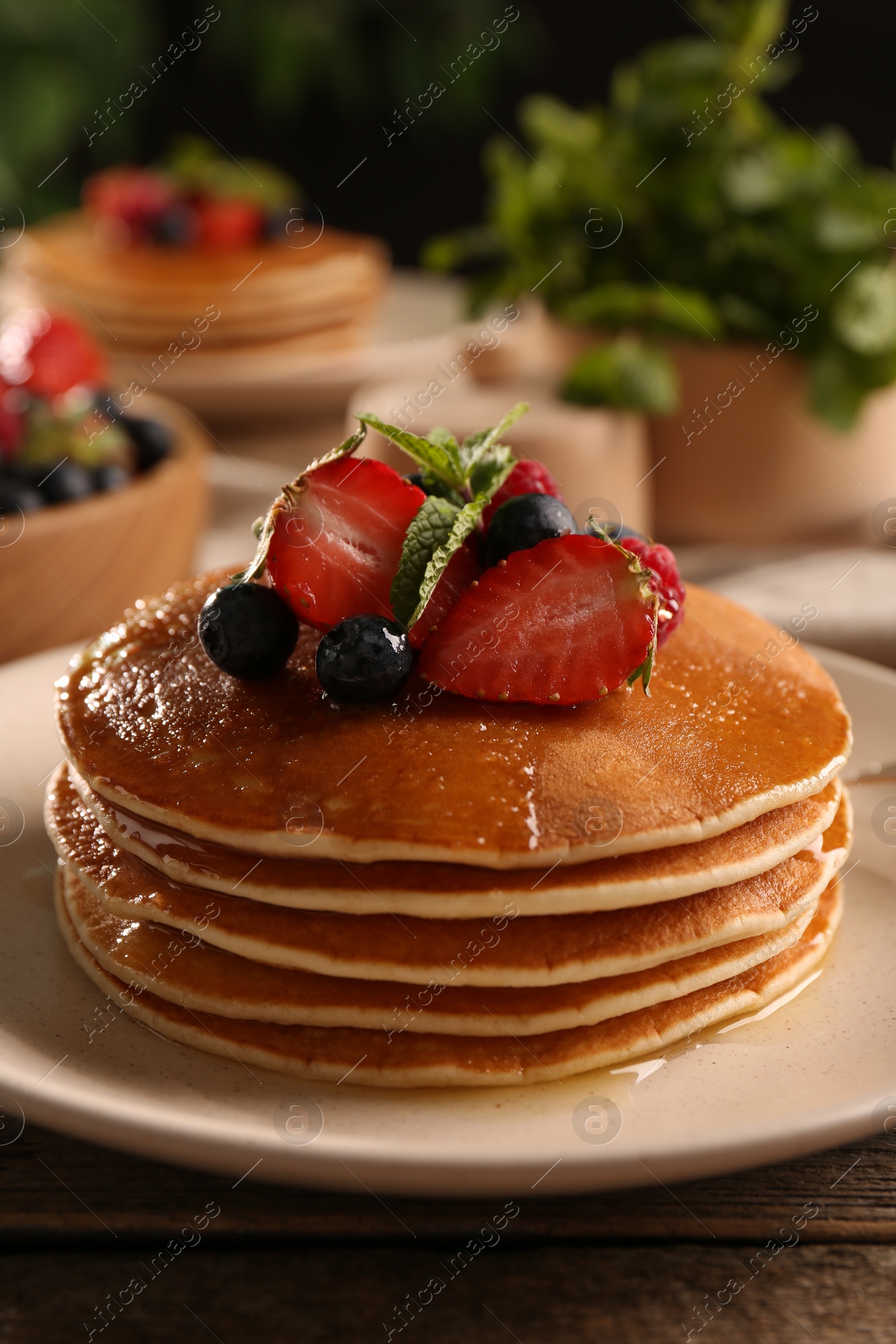 Photo of Tasty pancakes with fresh berries and mint on wooden table, closeup