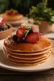 Photo of Tasty pancakes with fresh berries and mint on wooden table, closeup