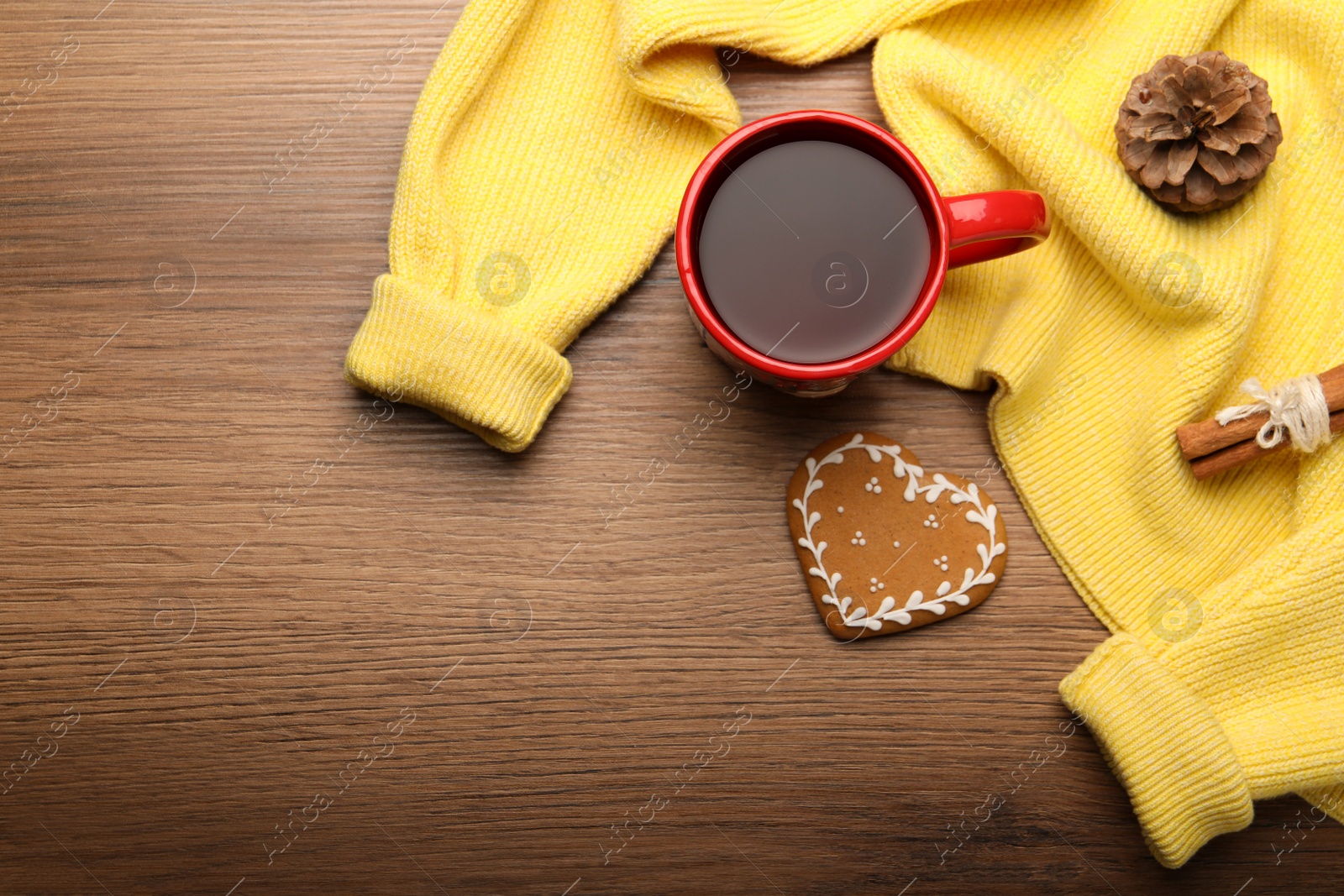 Photo of Cup of hot drink with yellow sweater and cookie on wooden table, flat lay. Space for text