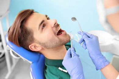 Photo of Professional dentist working with patient in modern clinic