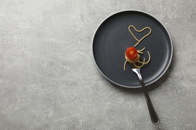Photo of Heart made of tasty spaghetti, fork and tomato on light grey table, top view. Space for text