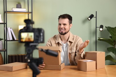 Smiling blogger with many parcels recording video at home