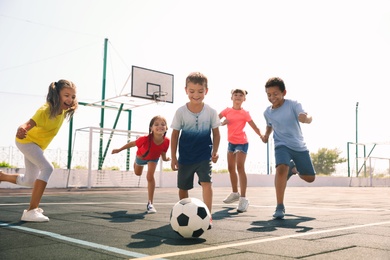 Cute children playing soccer outdoors on sunny day. Summer camp