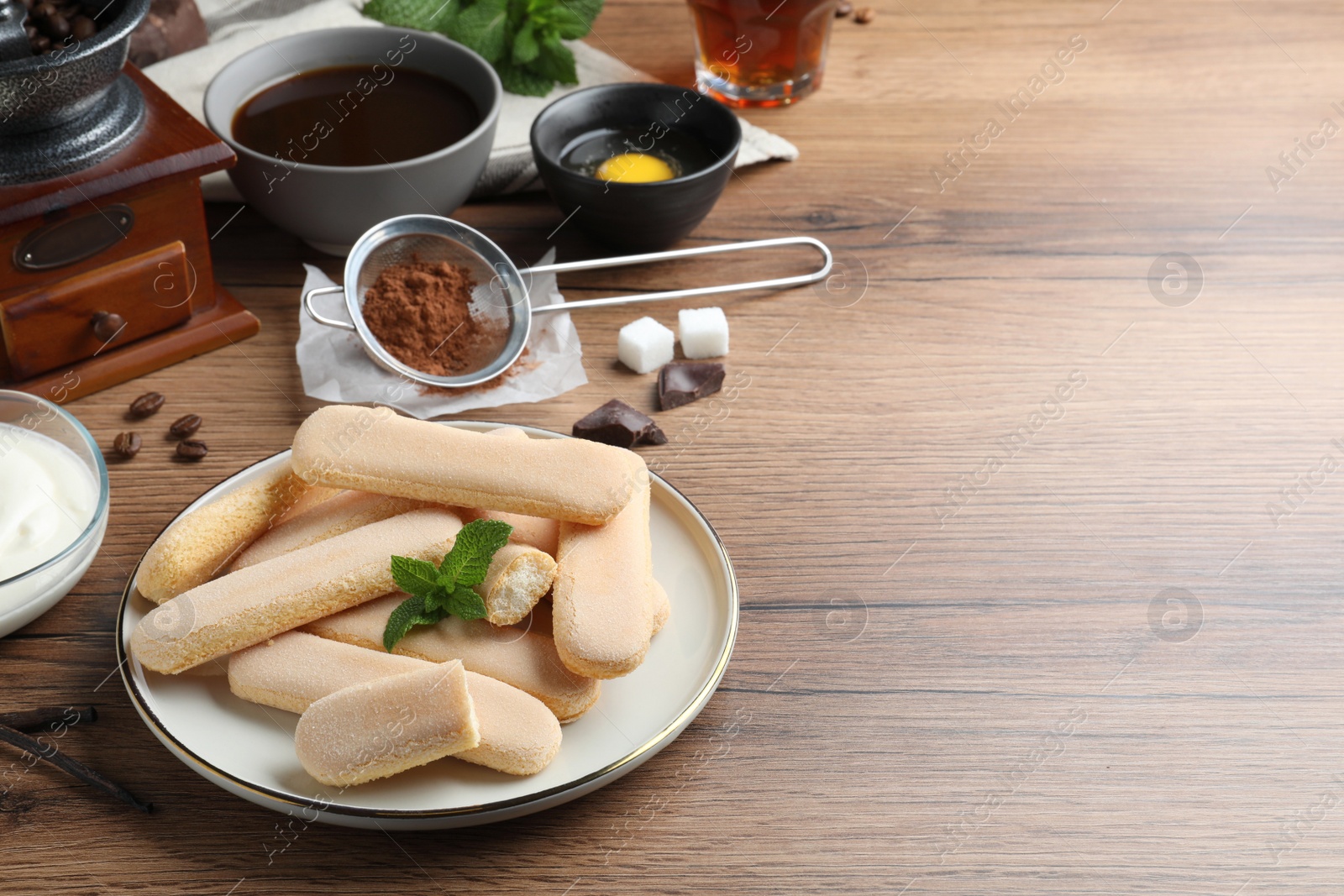 Photo of Tasty cookies and other tiramisu ingredients on wooden table, space for text