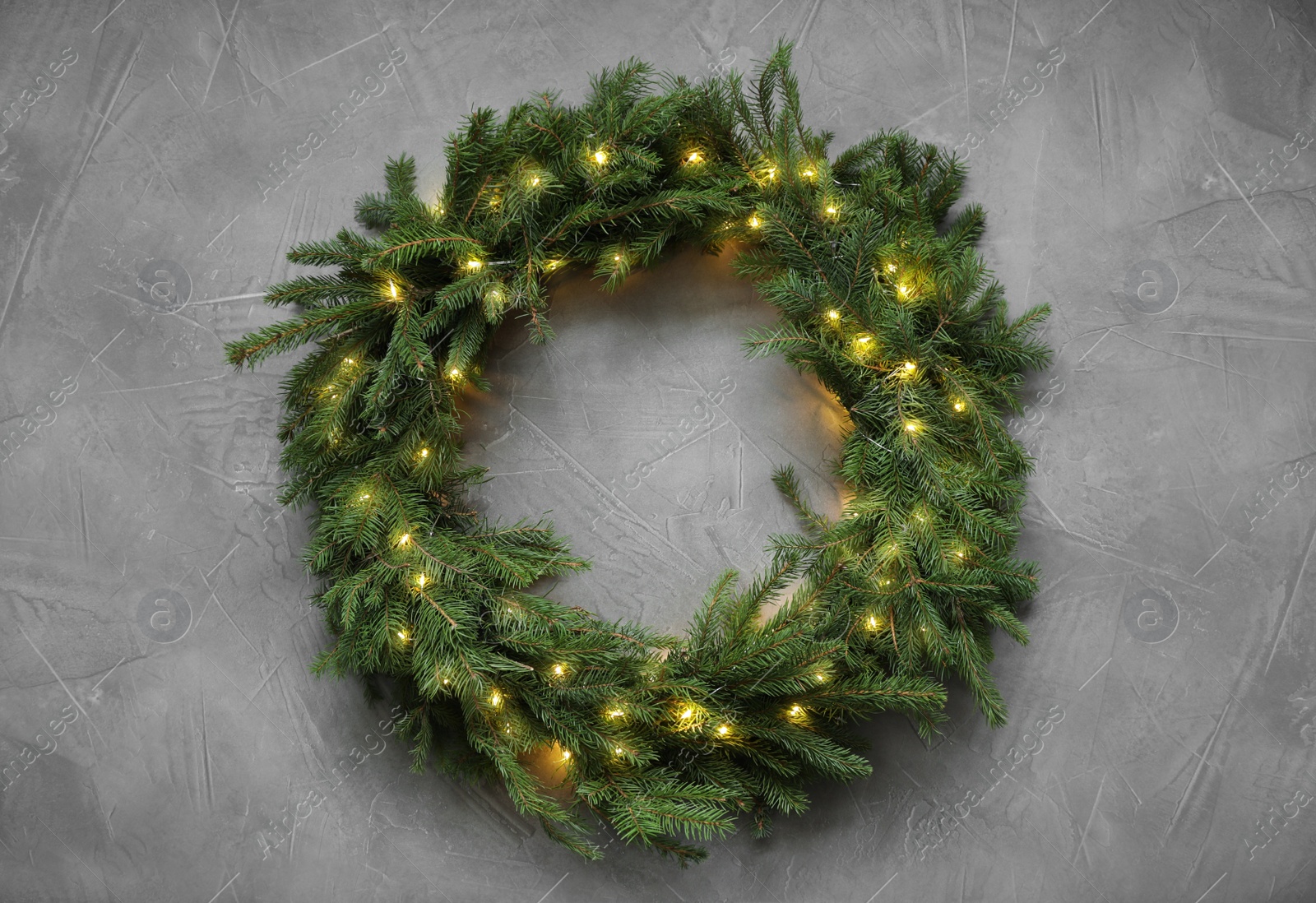 Photo of Beautiful Christmas wreath with festive lights on grey background, top view