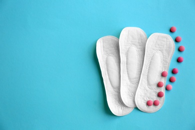 Photo of Flat lay composition with menstrual pads and pills on color background. Gynecological care