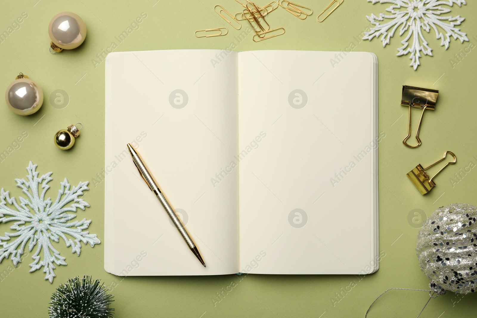 Photo of Open notebook, stationery and festive decor on light green background, flat lay. New Year aims