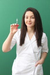 Photo of Cosmetologist in medical uniform with syringe on green background
