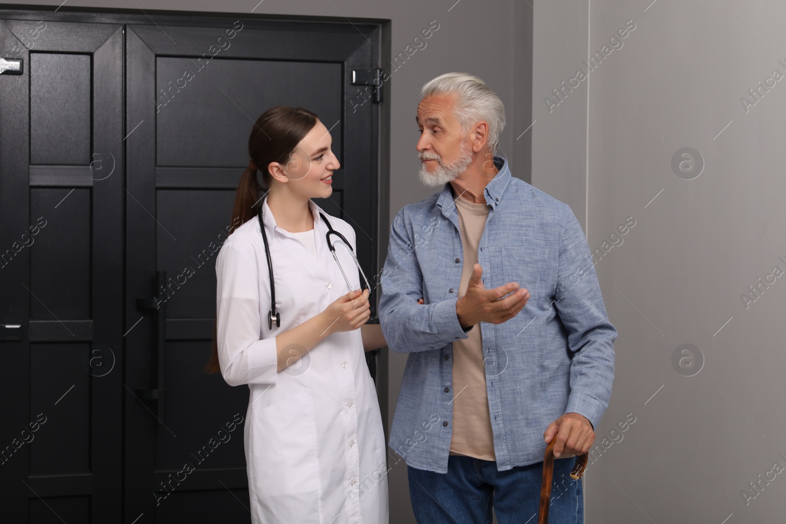 Photo of Young healthcare worker assisting senior man indoors