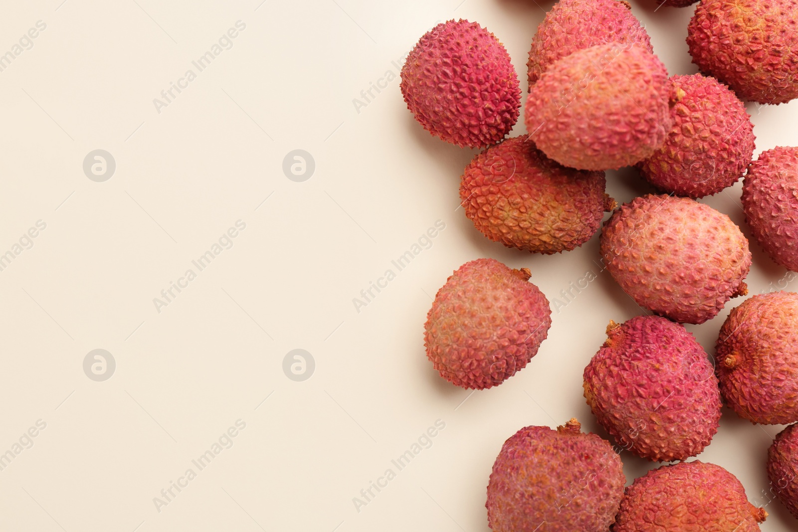 Photo of Fresh ripe lychees on beige background, flat lay. Space for text