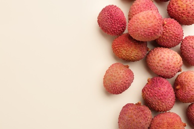Fresh ripe lychees on beige background, flat lay. Space for text