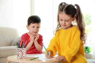 Photo of Cute little boy and girl drawing at table in living room