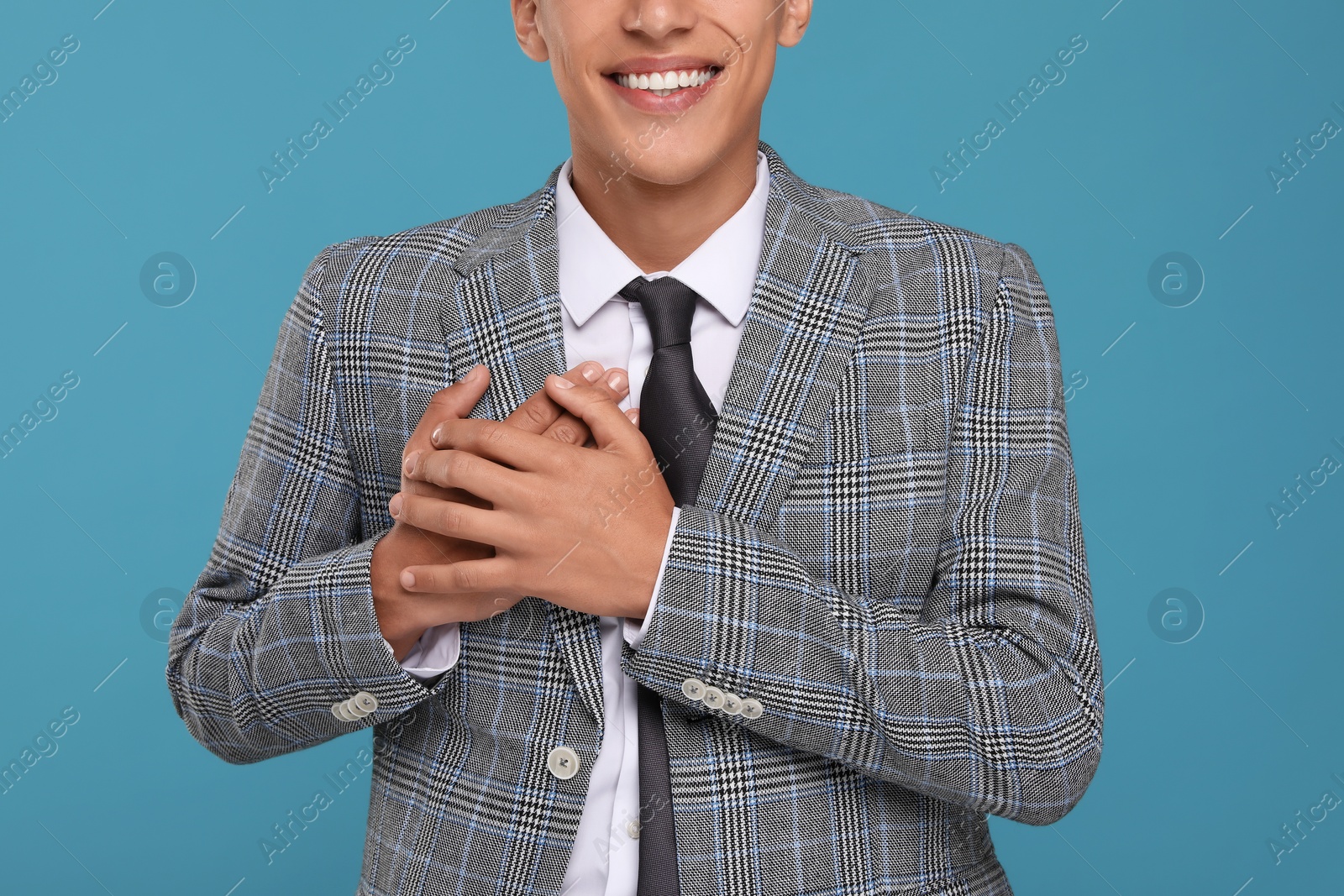 Photo of Thank you gesture. Grateful man with hands on chest against light blue background, closeup