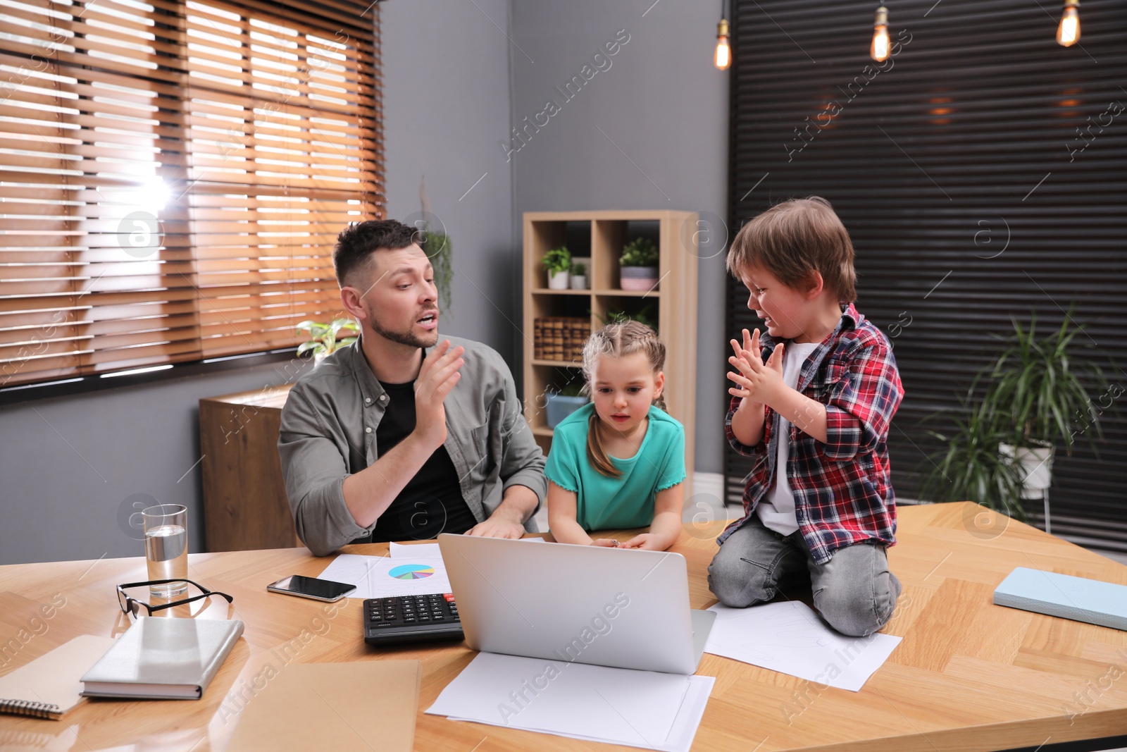 Photo of Overwhelmed man combining parenting and work at home