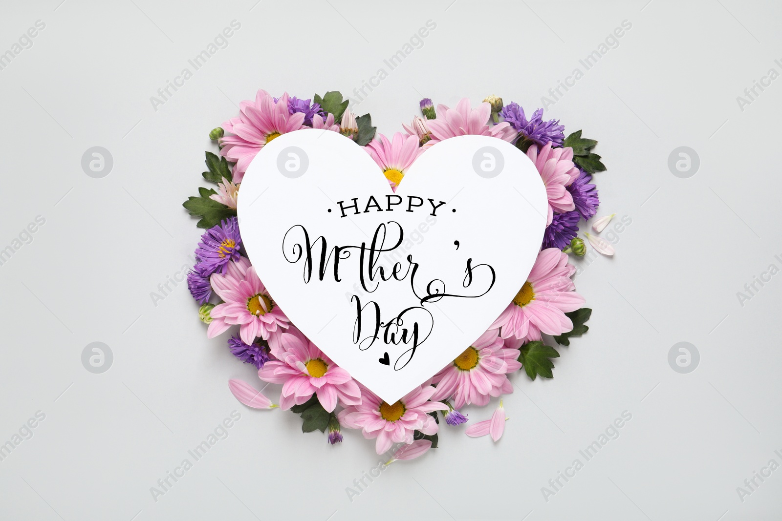 Image of Happy Mother's Day greeting card in shape of heart and beautiful flowers on white background, flat lay