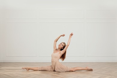 Photo of Beautiful professional dancer practicing split in studio