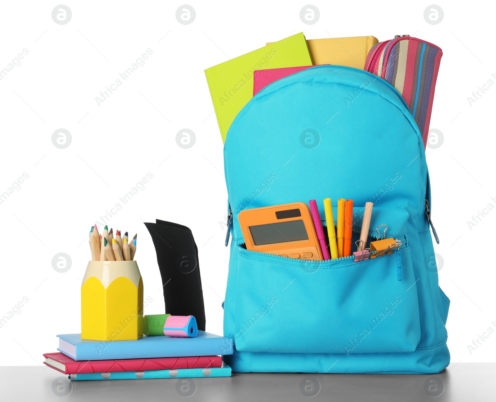 Photo of Bright backpack with school stationery on grey stone table against white background