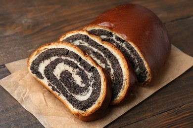 Photo of Cut poppy seed roll on wooden table, closeup. Tasty cake