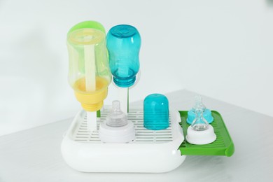 Photo of Dryer with baby bottles and nipples after sterilization on white table