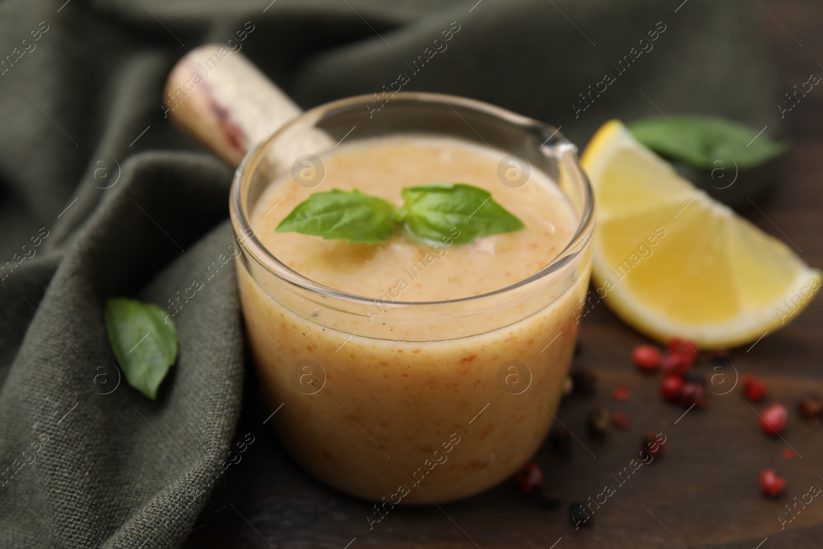 Photo of Delicious turkey gravy, basil, peppercorns and lemon on table, closeup