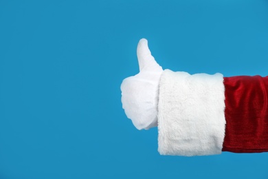 Photo of Santa Claus showing thumb up on blue background, closeup of hand