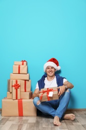 Young man with Christmas gifts near color wall