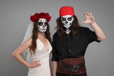 Photo of Couple in scary bride and pirate costumes on light grey background. Halloween celebration