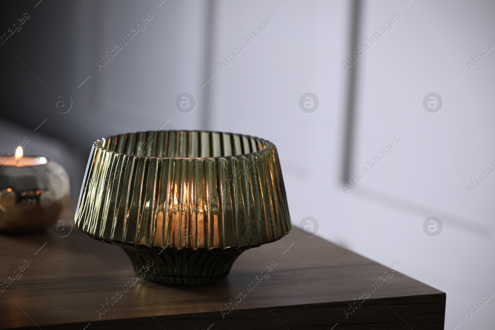 Photo of Stylish lantern with burning candle on wooden table indoors. Space for text