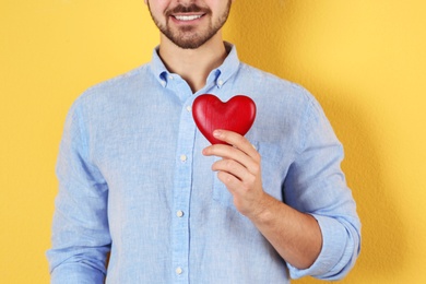 Photo of Man holding decorative heart on color background, closeup