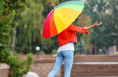 Young woman with bright umbrella under rain outdoors