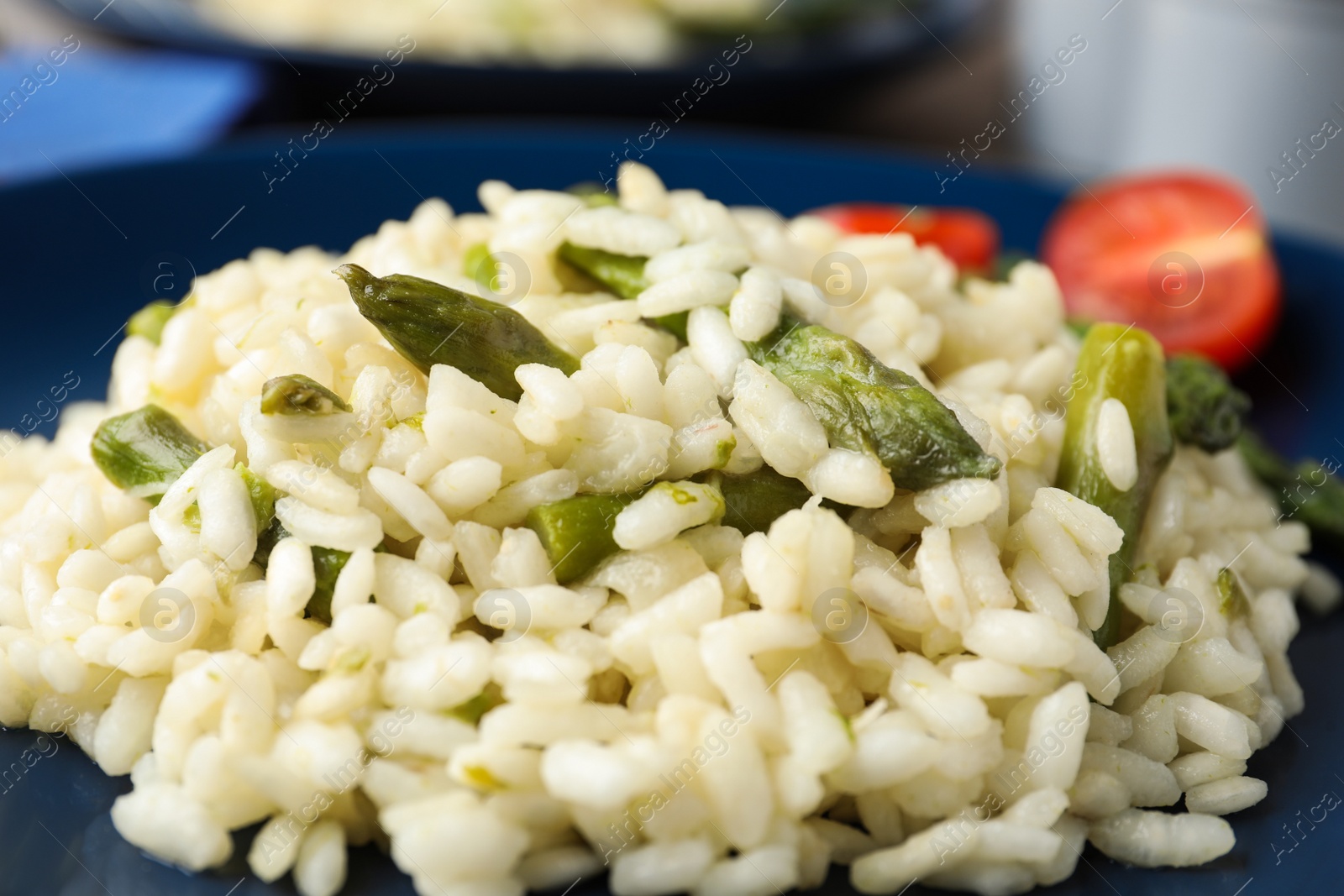 Photo of Delicious risotto with asparagus in plate, closeup